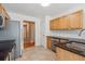 Kitchen with stainless steel appliances, wood cabinets, tile floors, and black countertops at 2410 Napa Valley Dr, Villa Rica, GA 30180