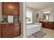 Bright bathroom featuring a soaking tub, wood cabinets, granite countertops, and a large mirror at 1019 Avonley Creek Trce, Sugar Hill, GA 30518