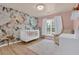 Charming Bedroom featuring floral wallpaper, a white crib, and hardwood floors at 1019 Avonley Creek Trce, Sugar Hill, GA 30518