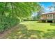 Expansive backyard featuring lush green grass, mature trees, and a charming back deck, ideal for outdoor enjoyment at 4866 S Lilburn Stone Mountain Road Sw Rd, Lilburn, GA 30047