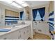 Bathroom with blue and white striped shower curtain, a large vanity, and a linen closet at 4866 S Lilburn Stone Mountain Road Sw Rd, Lilburn, GA 30047