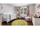 Bright and airy bedroom with wooden floors, a crib, and a rocker chair at 6492 Swift Creek Road, Lithonia, GA 30058