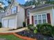 Two-story home with a two-car garage, a garden bed filled with flowers, and red shutters at 1447 Evanston, Marietta, GA 30062