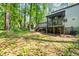 Exterior view of home backyard features a screened porch, wooden deck, and wooded yard on a sunny day at 2136 N Landing Way, Marietta, GA 30066