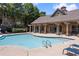 Community swimming pool surrounded by lounge chairs, lush landscaping, and brick clubhouse at 538 Sarabrook Pl, Sandy Springs, GA 30342