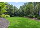 Wide shot of a backyard with lush green lawn and landscaped beds bordering the tree line at 4759 Highland Point Dr, Auburn, GA 30011