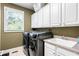 Modern laundry room with front-loading washer/dryer, white cabinets, and sink at 4759 Highland Point Dr, Auburn, GA 30011