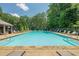 Community pool featuring a stone trim, various chairs, and surrounding trees at 3275 Cherry Oak Ln, Cumming, GA 30041