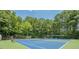 Two blue-surface tennis courts surrounded by lush greenery and fencing in the Northern Oaks community at 3275 Cherry Oak Ln, Cumming, GA 30041