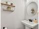 Powder room featuring a pedestal sink, framed round mirror, and modern shelving at 3374 Verdi Ln, Kennesaw, GA 30144