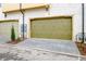 Exterior view of two-car garages with unique painted doors and paving stone driveway at 150 Rolison Way, Fayetteville, GA 30214