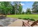 Landscaped backyard with patio, chair, and expansive lawn surrounded by mature trees at 200 Pine Tree Ln, Mcdonough, GA 30252