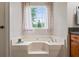Bright bathroom featuring a large soaking tub beneath a window with patterned curtains at 200 Pine Tree Ln, Mcdonough, GA 30252