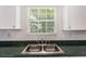 Stainless steel kitchen sink with green countertop and white cabinets, lit by a window view at 2601 Brandenberry Dr, Decatur, GA 30034