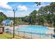 Community pool with lounge chairs, umbrellas and a neighboring clubhouse and lake at 2500 Ashbourne Dr, Lawrenceville, GA 30043