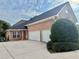 Side view of a brick home featuring an attached three-car garage and large driveway at 3580 Canon Creek Dr, Cumming, GA 30041