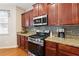 Modern kitchen with stainless steel gas range, granite countertops, tile backsplash, and rich wood cabinetry at 6202 Oakdale Ridge Se Ct, Mableton, GA 30126