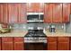 Close up view of a kitchen featuring a modern stainless steel range, granite countertops, and dark wood cabinets at 6202 Oakdale Ridge Se Ct, Mableton, GA 30126