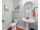 This powder room has a pedestal sink, decorative mirror, and wood-look flooring for simple elegance at 6202 Oakdale Ridge Se Ct, Mableton, GA 30126