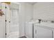 Laundry room with tile floor, white shiplap walls, with washer, dryer, and bathroom in view at 2121 Jep Wheeler Rd, Woodstock, GA 30188