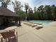 Community swimming pool surrounded by lounge chairs and outdoor seating with many mature trees at 2873 Shoals Hill Ct, Dacula, GA 30019