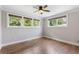 Spacious bedroom with hardwood floors, light gray paint, three windows, and a ceiling fan at 4847 Lakewood Dr, Acworth, GA 30101