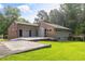 Attractive single-story home featuring gray siding, brick accents, and a large concrete patio in a lush, green yard at 4847 Lakewood Dr, Acworth, GA 30101