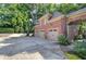 Spacious three-car garage with ample parking on a wide driveway, surrounded by mature trees and landscaping at 2160 Kensington Gates Nw Dr, Kennesaw, GA 30152