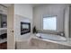 Luxurious bathroom featuring a soaking tub with tiled surround and fireplace at 2160 Kensington Gates Nw Dr, Kennesaw, GA 30152