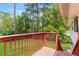 Outdoor wooden deck with red railing offers views of the lawn and mature trees at 4133 Conley Circle Cir, Conley, GA 30288