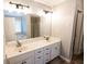 Bathroom featuring double sinks, vanity with dark hardware, large mirror, and a window at 1200 Martins Chapel Se Ln, Lawrenceville, GA 30045