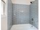 Remodeled bathroom with new gray tile, updated shower head, and a bright window at 1560 Pontiac Se Pl, Atlanta, GA 30315
