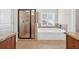 Bathroom showcasing a walk-in shower with glass door and a separate soaking tub beneath a bright window at 5740 Zelkova Dr, Cumming, GA 30040