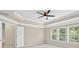 Bedroom with neutral walls and carpet, ceiling fan, tray ceiling and windows at 5740 Zelkova Dr, Cumming, GA 30040