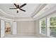 Bedroom with neutral walls and carpet, ceiling fan, tray ceiling and windows at 5740 Zelkova Dr, Cumming, GA 30040