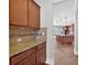 Convenient butler's pantry with granite countertops and brown wood cabinetry leading into the kitchen at 5740 Zelkova Dr, Cumming, GA 30040