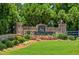 Stone-clad entrance to the community, featuring colorful flowers and manicured greenery at 5740 Zelkova Dr, Cumming, GA 30040