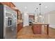 Modern kitchen with stainless steel refrigerator, wood cabinets, granite countertops, and a kitchen island with pendant lighting at 5740 Zelkova Dr, Cumming, GA 30040