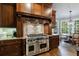 Close up of a gourmet kitchen featuring a stainless steel range, custom hood, and wood cabinets with granite countertops at 1412 Lanier Ne Mnr, Atlanta, GA 30319