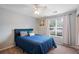 A bedroom with a blue bed, light grey walls, ceiling fan, and natural light from the window at 1602 Buckingham Place Pl, Woodstock, GA 30188