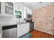 Kitchen featuring white cabinets, granite countertops, stainless steel appliances, and a brick accent wall at 1602 Buckingham Place Pl, Woodstock, GA 30188