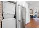 This open concept view showcases the laundry, refrigerator, and living room with hardwood floors at 1602 Buckingham Place Pl, Woodstock, GA 30188