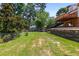 The home has a sprawling backyard featuring a tiered lawn, mature trees, fountain, and a wood deck with seating at 7575 Hunters Woods W Dr, Atlanta, GA 30350