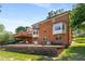 View of the brick home featuring a covered patio and outdoor seating area with a retaining wall and lush lawn at 7575 Hunters Woods W Dr, Atlanta, GA 30350