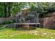 An in-ground trampoline sits on the lush lawn in the backyard with landscaped, terraced levels and mature trees at 7575 Hunters Woods W Dr, Atlanta, GA 30350