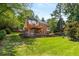 Back exterior view of brick home with expansive tiered backyard featuring wood deck, patio, trampoline, and water fountain at 7575 Hunters Woods W Dr, Atlanta, GA 30350