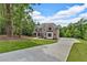 View of a long concrete driveway leading to a two-story brick home surrounded by lush trees at 7449 Waterview Cv, Douglasville, GA 30135