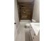 Bathroom featuring custom shower panel with wood-look tile surround, white fixtures, and a decorative inset shelf at 1090 Coleman Sw St, Atlanta, GA 30310