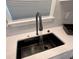 Modern kitchen featuring a sleek black waterfall sink with a pull-down faucet and gray subway tile backsplash at 1090 Coleman Sw St, Atlanta, GA 30310