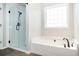 Bathroom featuring glass-enclosed shower, soaking tub, and a large window providing natural light at 4776 Harrod Ct, Douglasville, GA 30135